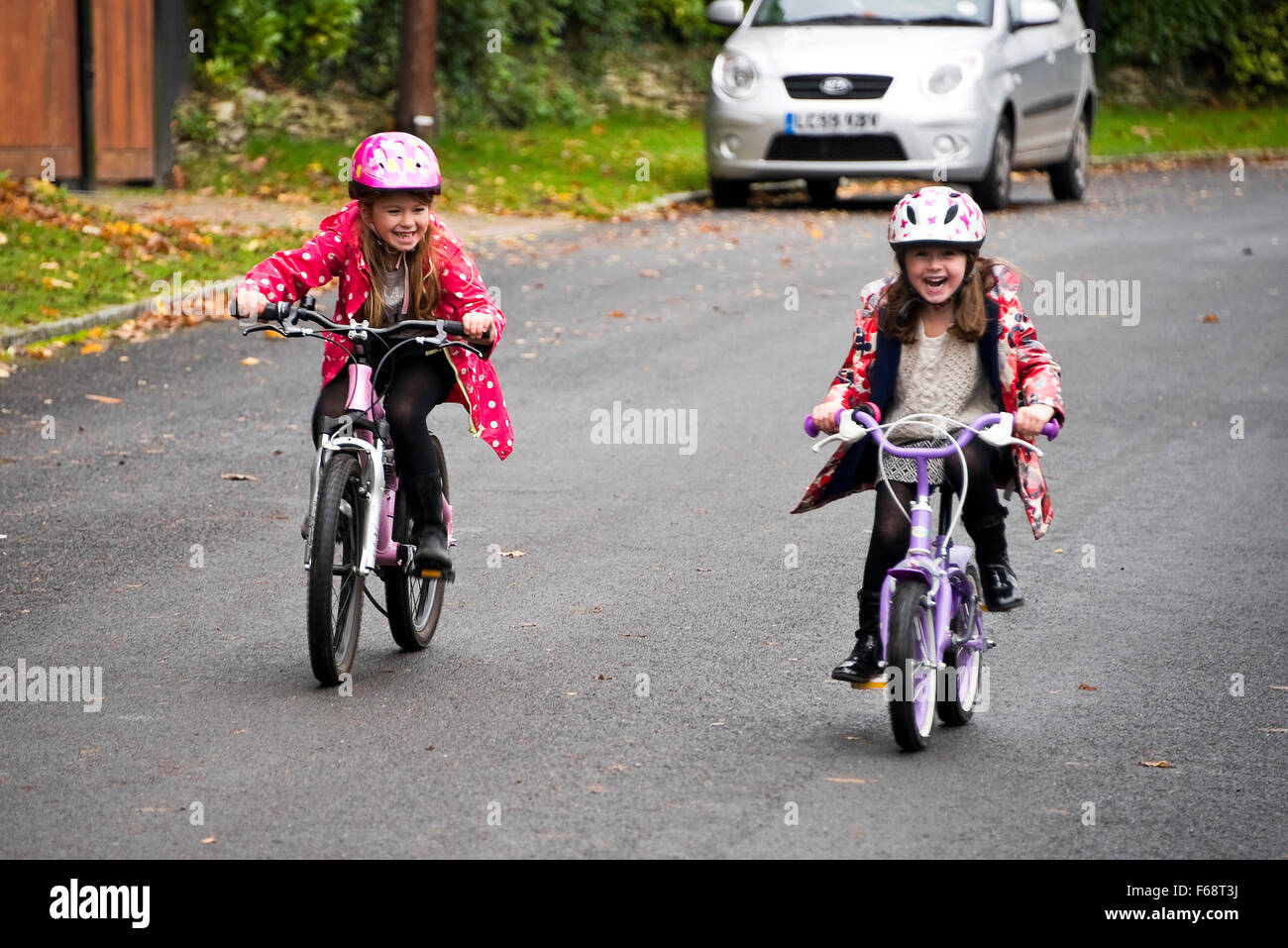 Horizontal portrait of young girls racing their bikes along the road. Stock Photo