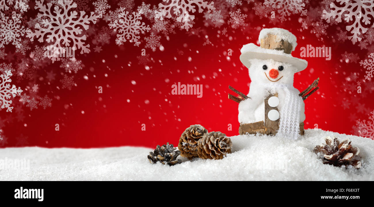 Modern red seasonal background with a cute happy snowman in the snow, ideal for Christmas or winter season Stock Photo