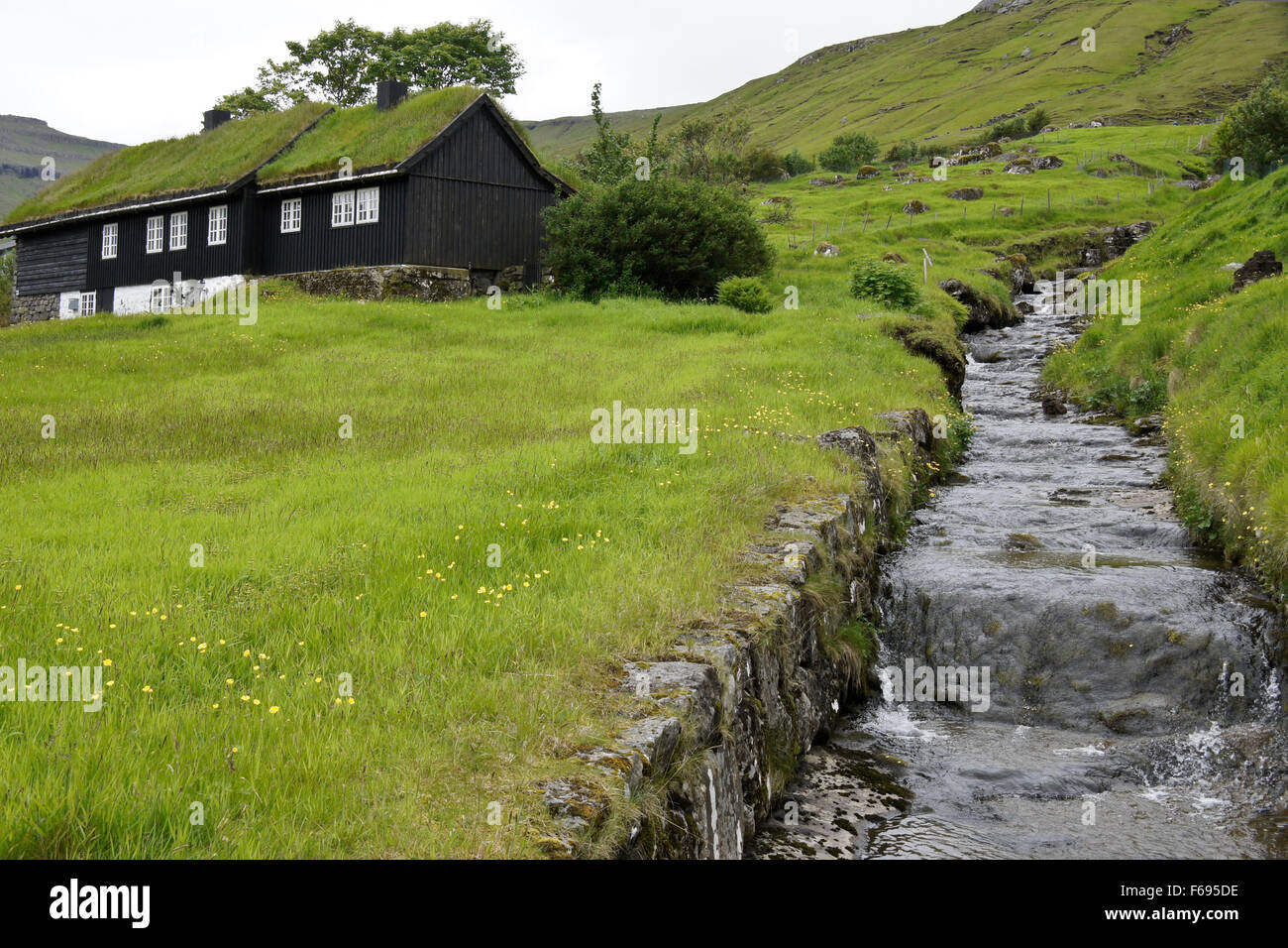 Turf-roofed house beside stream, Kollafjordur, Stremoy, Faroe Islands Stock Photo