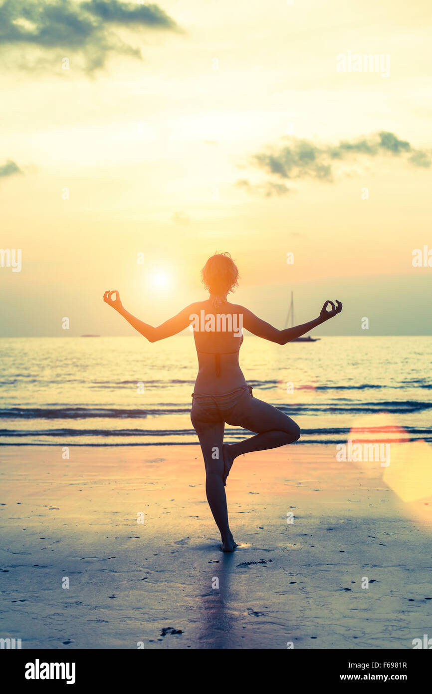Female silhouette in yoga meditation pose at sunset Stock Photo - Alamy