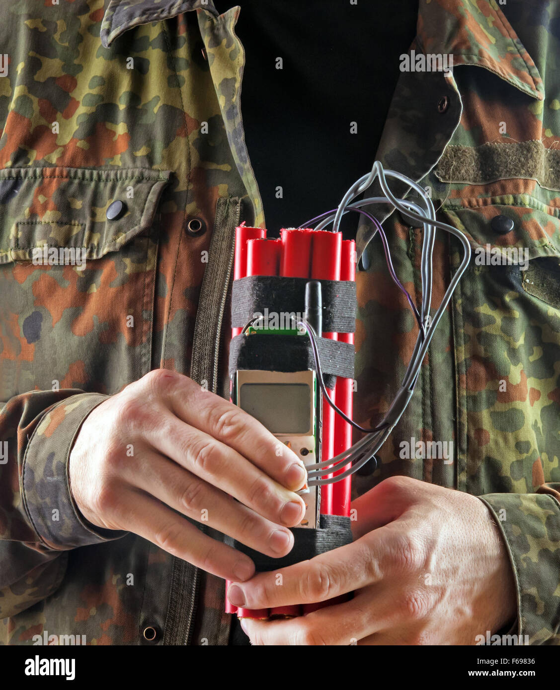 man in a military jacket with explosives and detonator holds in hands Stock Photo