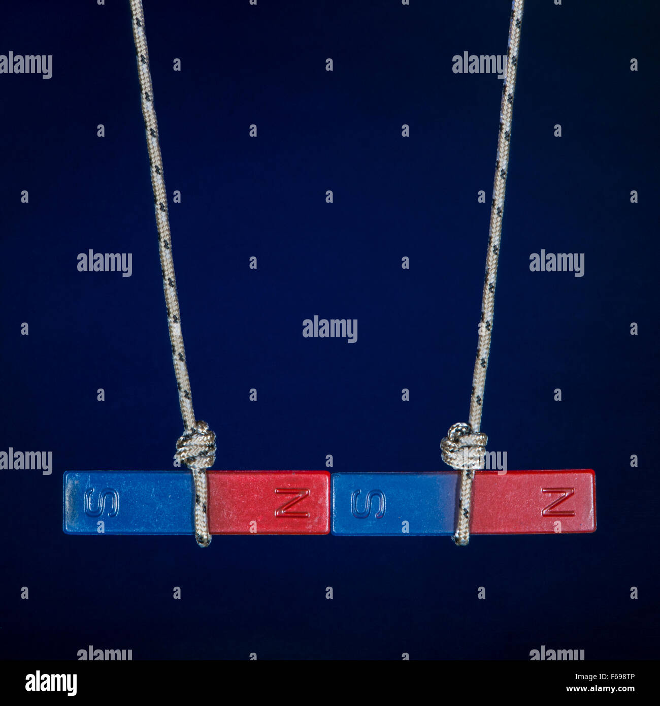 When the matching poles of two magnets hanging on strings face each other, the magnets repel one another. Stock Photo