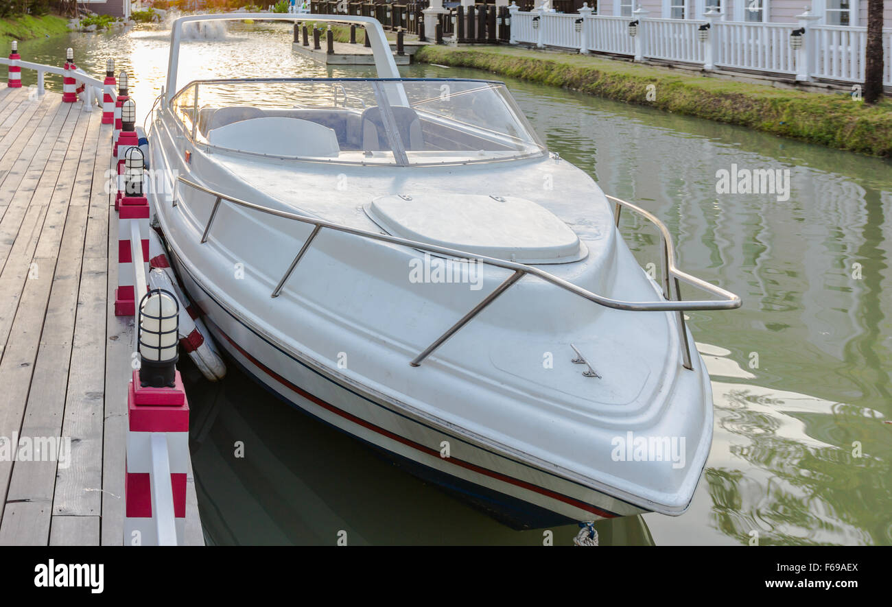 A white speedboat docked on a river Stock Photo