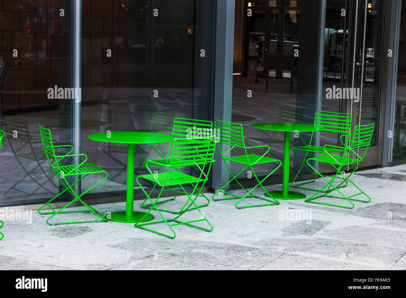Green table and chairs outside downtown building Stock Photo