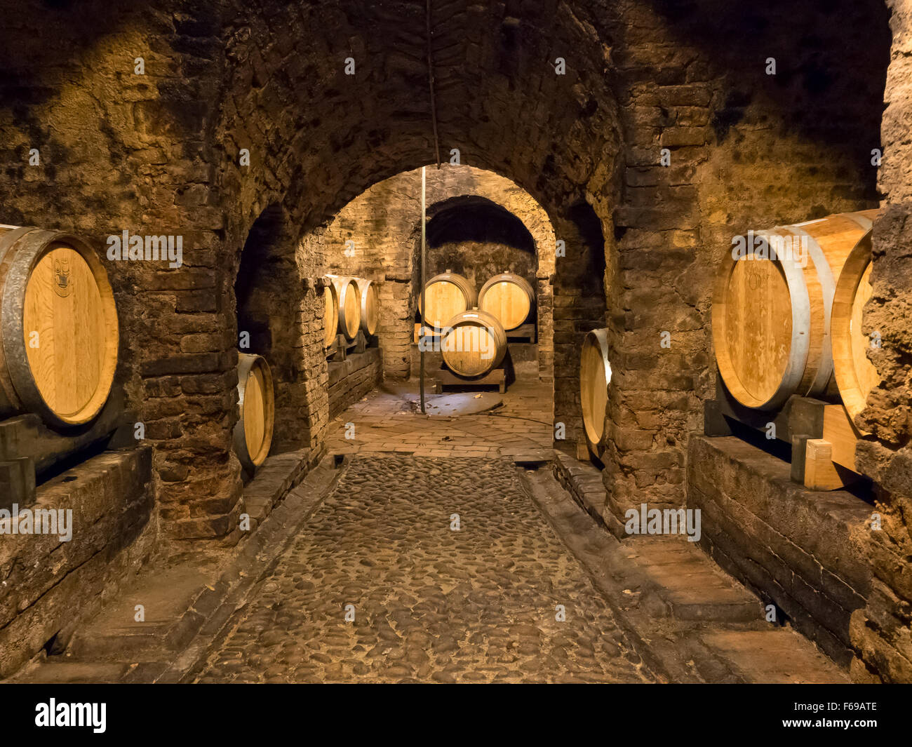 Several wooden wine barrels stocked in an ancient medieval cellar located in Neive, town in Langhe region. Stock Photo