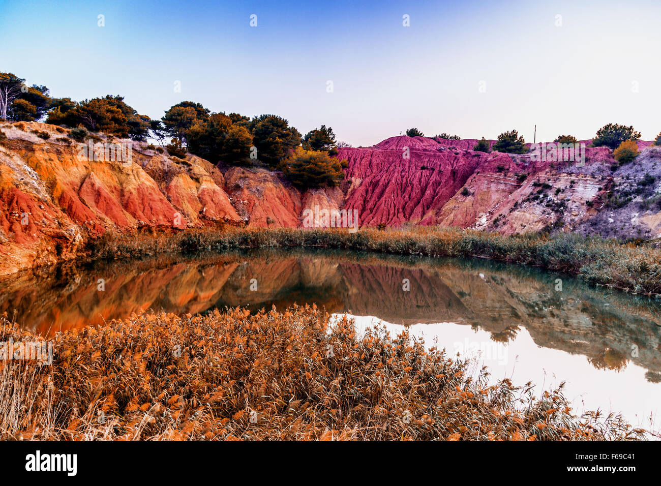 red soils around the freshwater lake formed in a former quarry for the extraction of bauxite in Italy Stock Photo