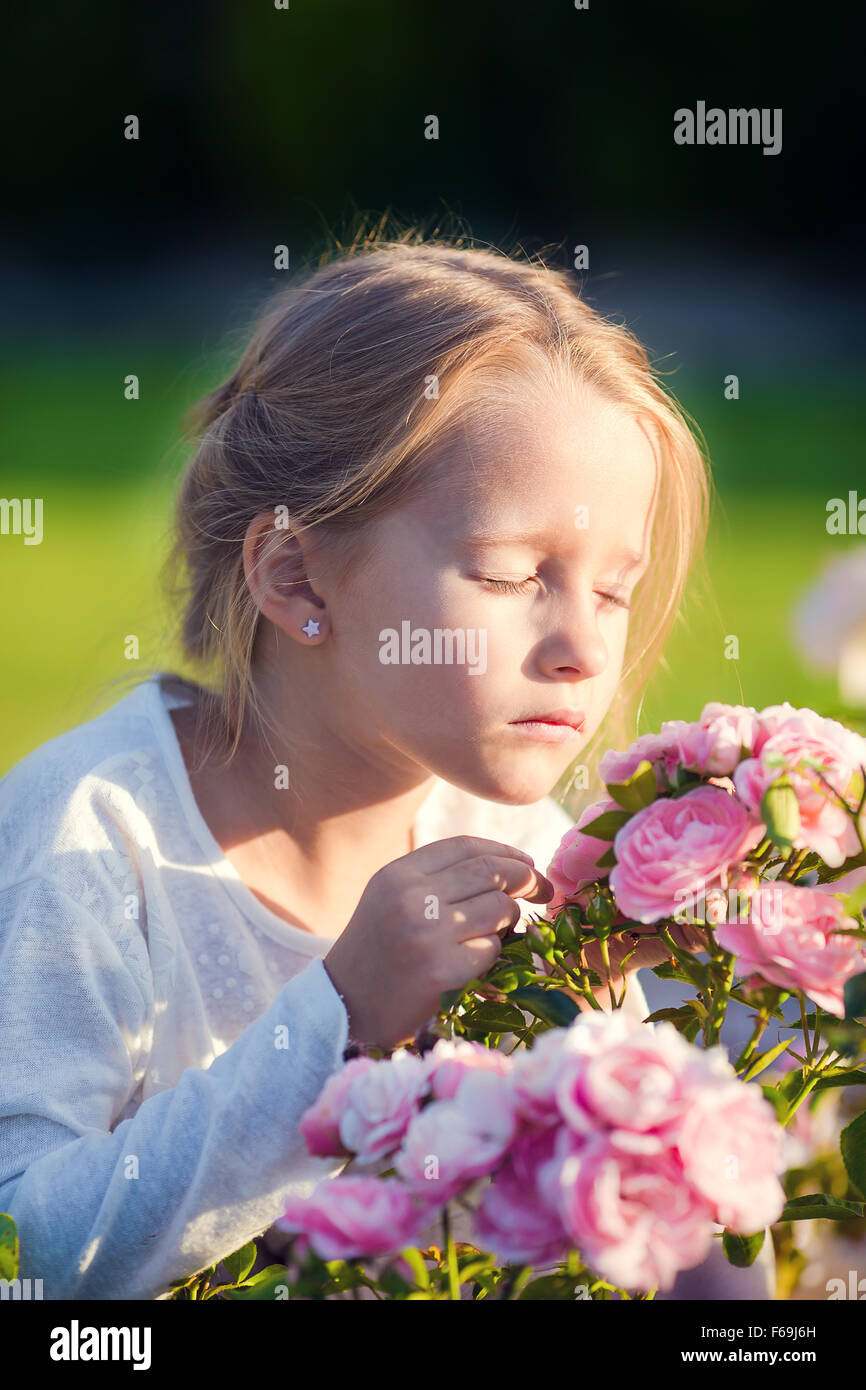 Little adorable girl smelling colorful flowers outdoors Stock Photo - Alamy