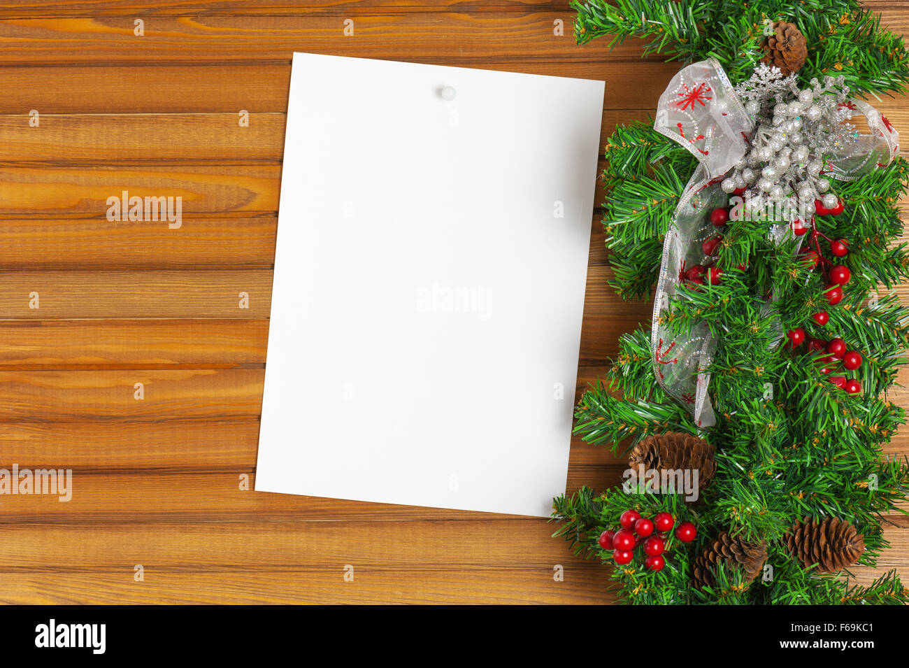 Christmas garland from pine tree and sheet of paper on wooden background. Stock Photo