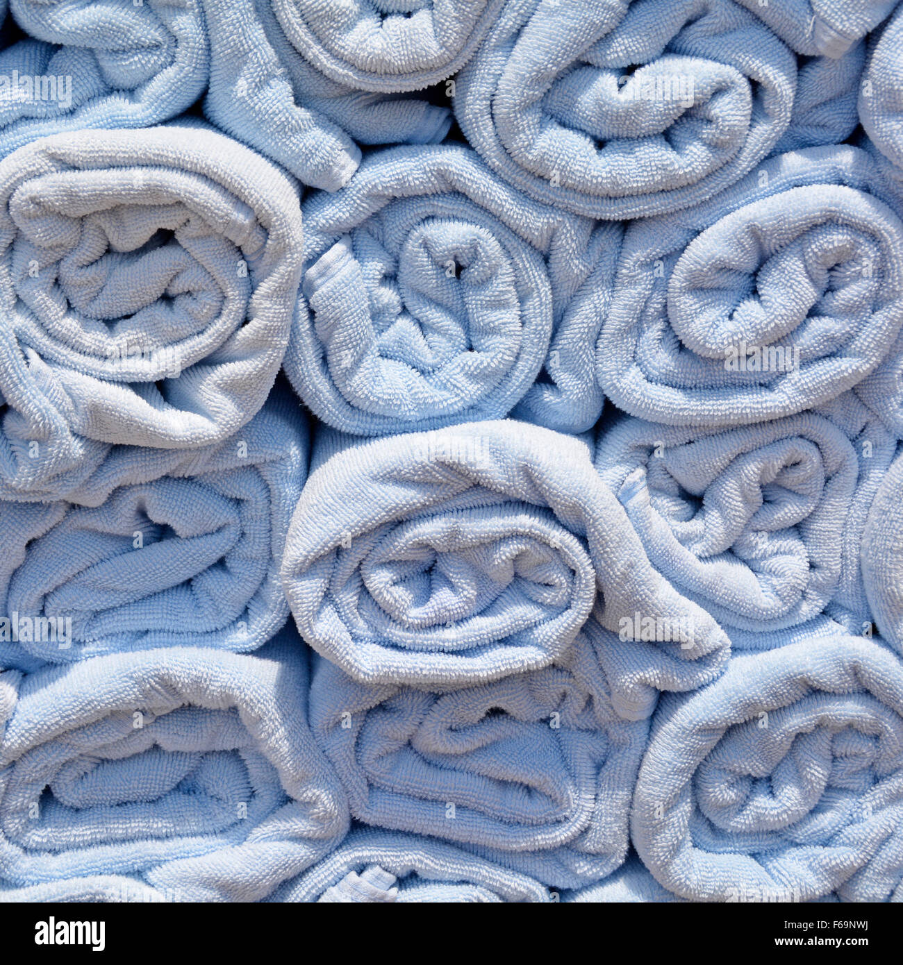 Abstract background end view close up of blue rolled up towel in stacks beside pool awaiting use by cruise ship passengers to place on sun loungers Stock Photo