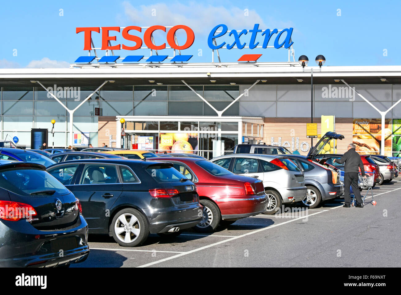 Supermarket Tesco Extra car park shopper loading trolley contents into car boot at East London store obscured number plates England UK Stock Photo