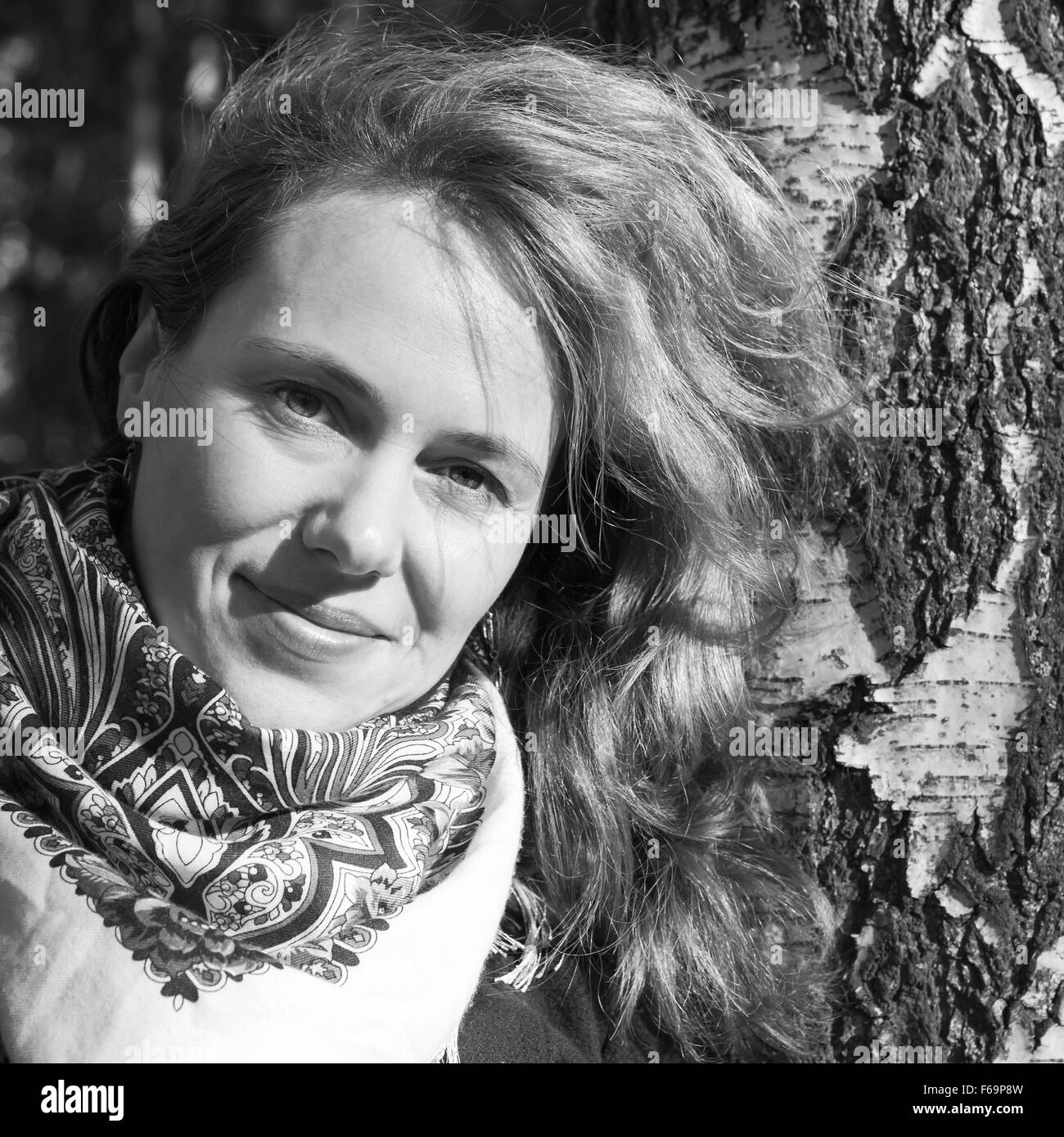 Outdoor monochrome portrait of smiling Young Caucasian woman in traditional Russian Pavloposadskie neck scarf Stock Photo