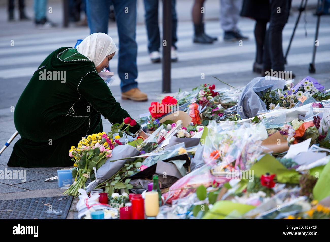 Paris, France. 15th Nov, 2015. A woman places flowers in front of the restaurant 'Petit Cambodge' in the Rue Alibert in Paris, France, 15 November 2015. At least 129 people were killed in a series of terrorist attacks in Paris, on 13 November 2015. Credit:  dpa picture alliance/Alamy Live News Stock Photo