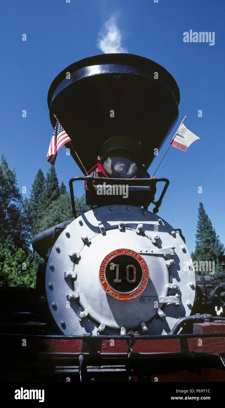 Visitors can experience bygone days in the Sierra National Forest by riding a logging train pulled by an historic steam locomotive operated by the Yosemite Mountain Sugar Pine Railroad from Fish Camp in California, USA. The Shay engine No. 10 was built in 1928 in Lima, Ohio, weighs 84 tons, and makes four-mile, hour-long excursions March through October. This close-up view of the front end shows its smokestack, headlight, the door to the smokebox, and the manufacturer's emblem with the locomotive's identity number. Stock Photo