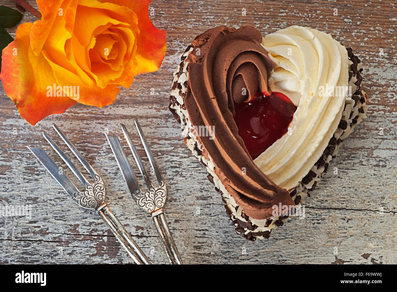Still life with heart-shaped cake, two ornate pastry forks and an orange rose Stock Photo