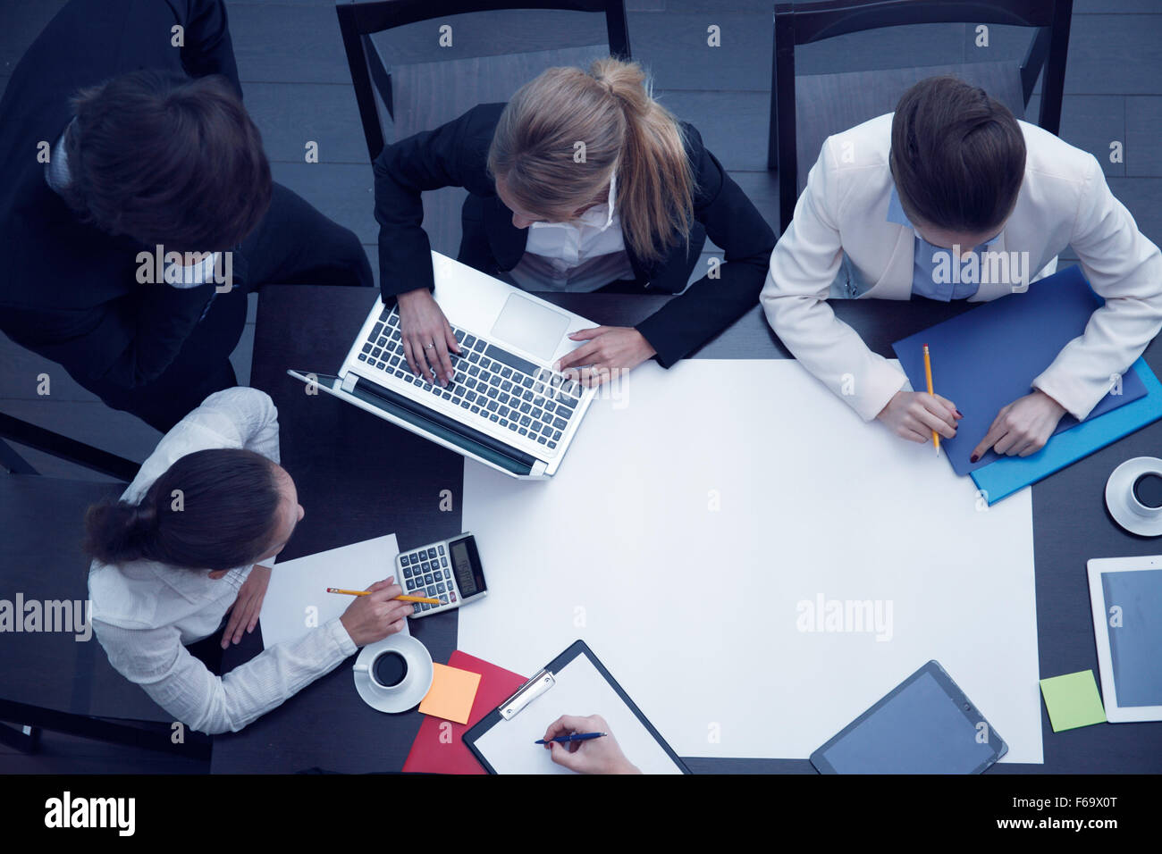 Business workplace with people, cup of coffee, digital tablet, smartphone, papers and various office objects on table Stock Photo