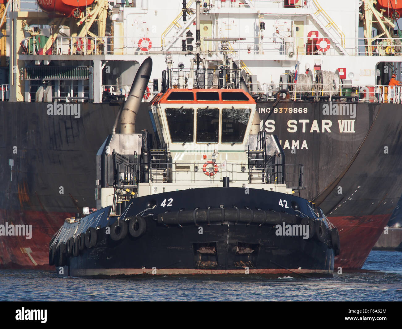 The tugboat 42 is seen towing the vessel Genius Star through the Port of Antwerp. This image highlights the logistical coordination and transport operations in a busy European port, with a focus on container shipping and maritime logistics. Stock Photo