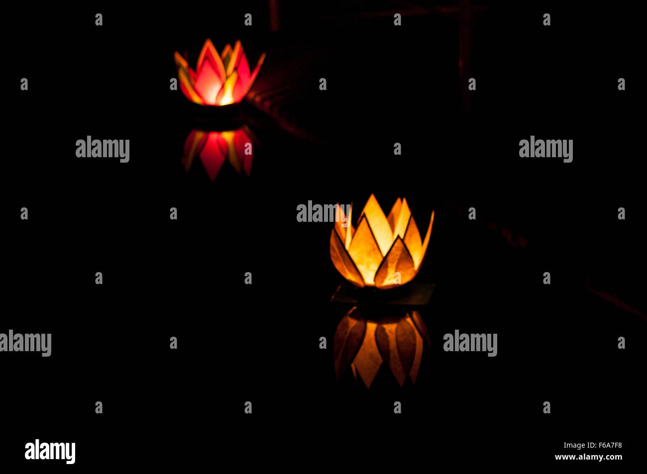 Flower-shaped floating candles at night, reflecting in the water. Stock Photo