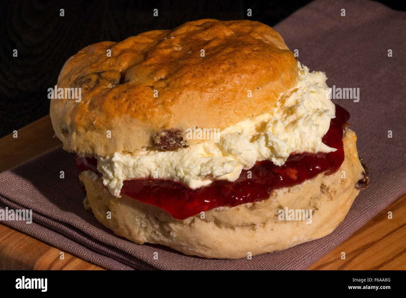 Freshly baked and served scone packed full of delicious strawberry jam and Cornish clotted cream Stock Photo