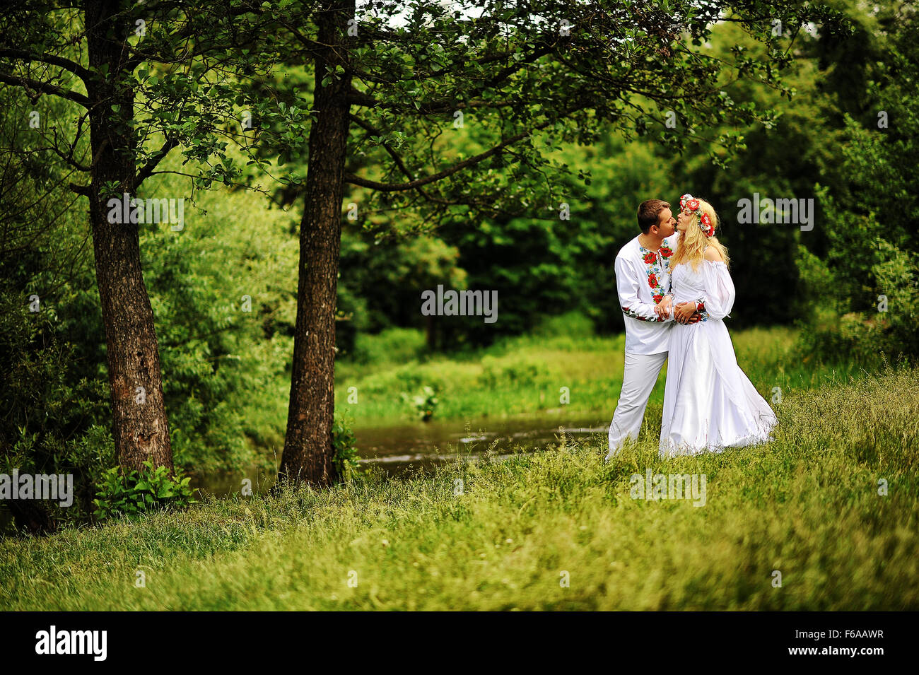Young beautiful couple in traditional dress under the tree Stock Photo ...
