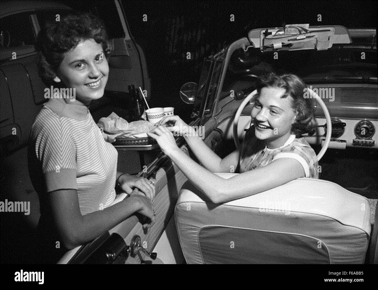 A group of teenagers enjoying a night out at a drive-in movie theater in Tallahassee. The scene captures a popular pastime from the mid-20th century, where young people would gather to watch films from their cars. This social event reflects the cultural trends of the 1950s and 1960s. Stock Photo