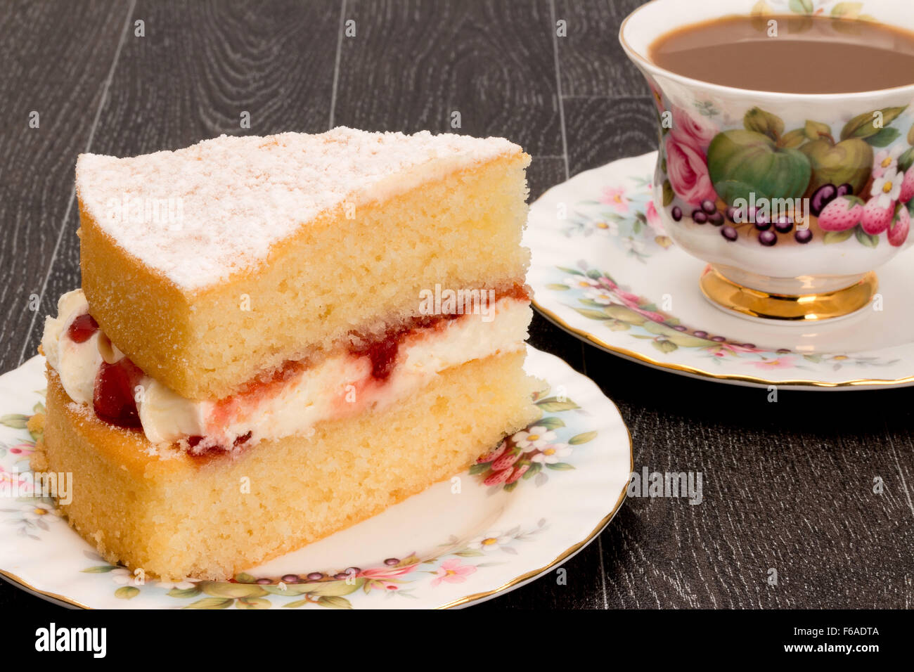 A slice of Victoria sponge cake and a cup of coffee with antique ornate crockery - studio shot. Stock Photo