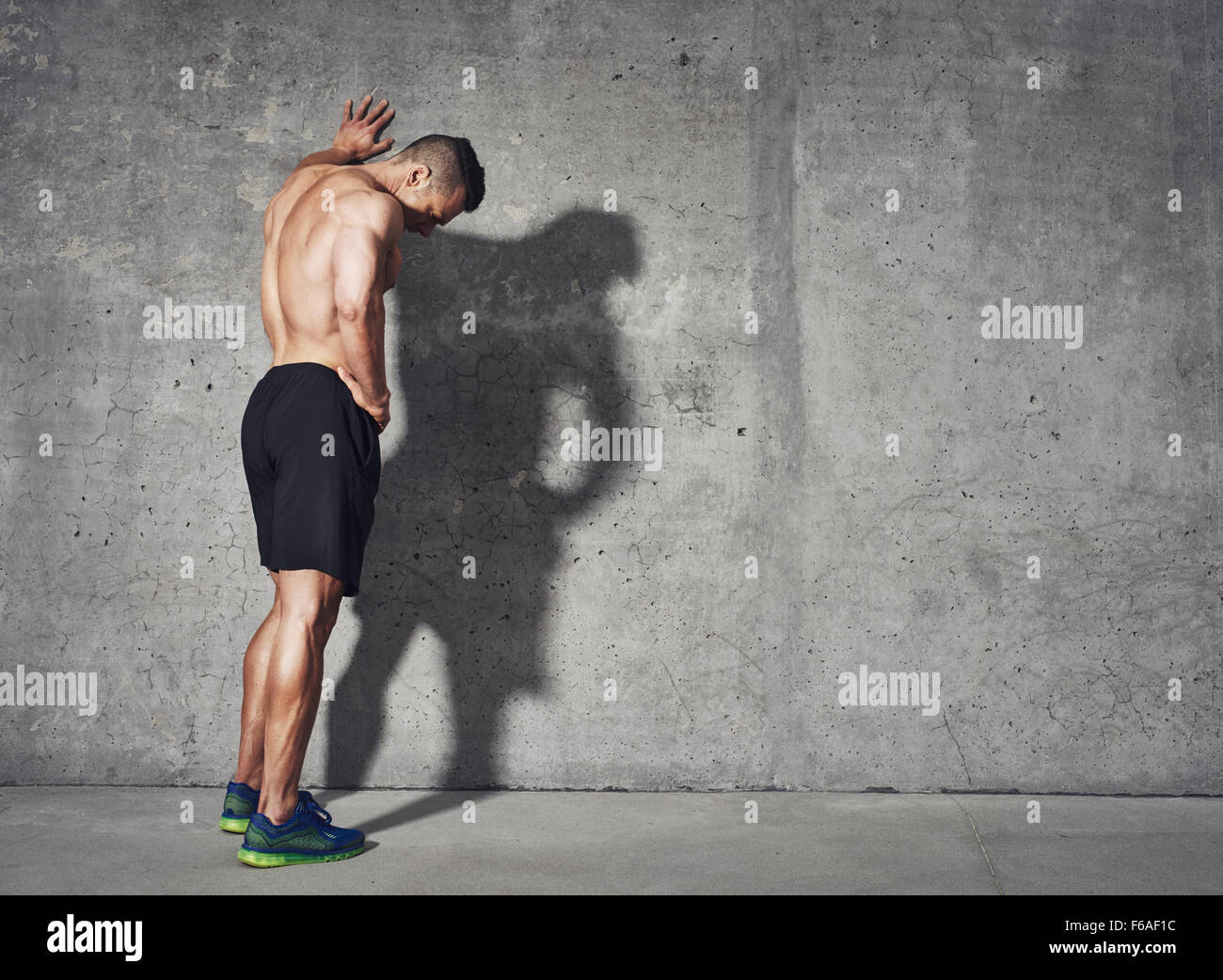 Young man resting after an active fitness training while standing against gray wall with copy space area for your text message, Stock Photo