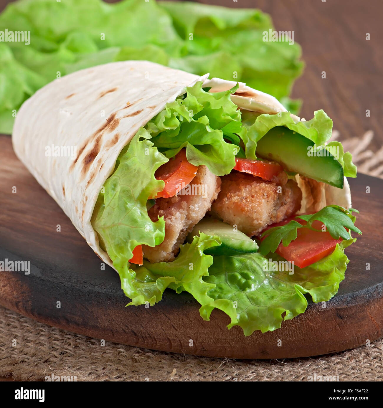 Fresh tortilla wraps with chicken nuggets and vegetables on plate Stock