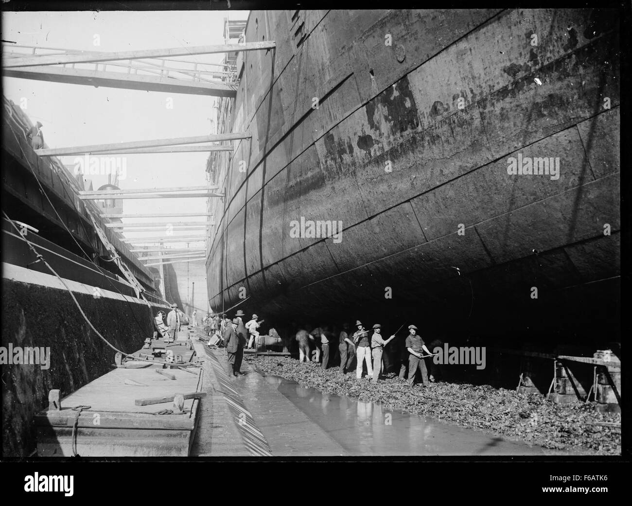 This historical image shows men working on the hull of a ship ...