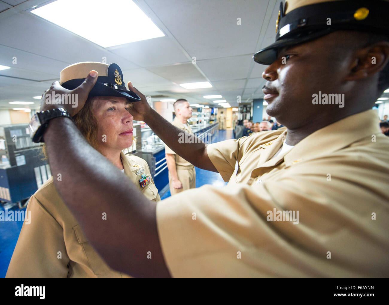 150915-N-XQ474-073 PORT AU PRINCE, Haiti (Sept. 16, 2015) Chief Hospital Corpsman Kevin Robinson, right, a native of Crawfordsville, Ark., assigned to Naval Medical Center Portsmouth, Va., places a combination cover on Chief Mass Communication Specialist Amy Kirk, a native of Eden, N.C., assigned to Navy Public Affairs Support Element East, Norfolk, Va., during the chief petty officer pinning ceremony aboard the Military Sealift Command hospital ship USNS Comfort (T-AH 20), during Continuing Promise 2015. Continuing Promise is a U.S. Southern Command-sponsored and U.S. Naval Forces Southern Co Stock Photo