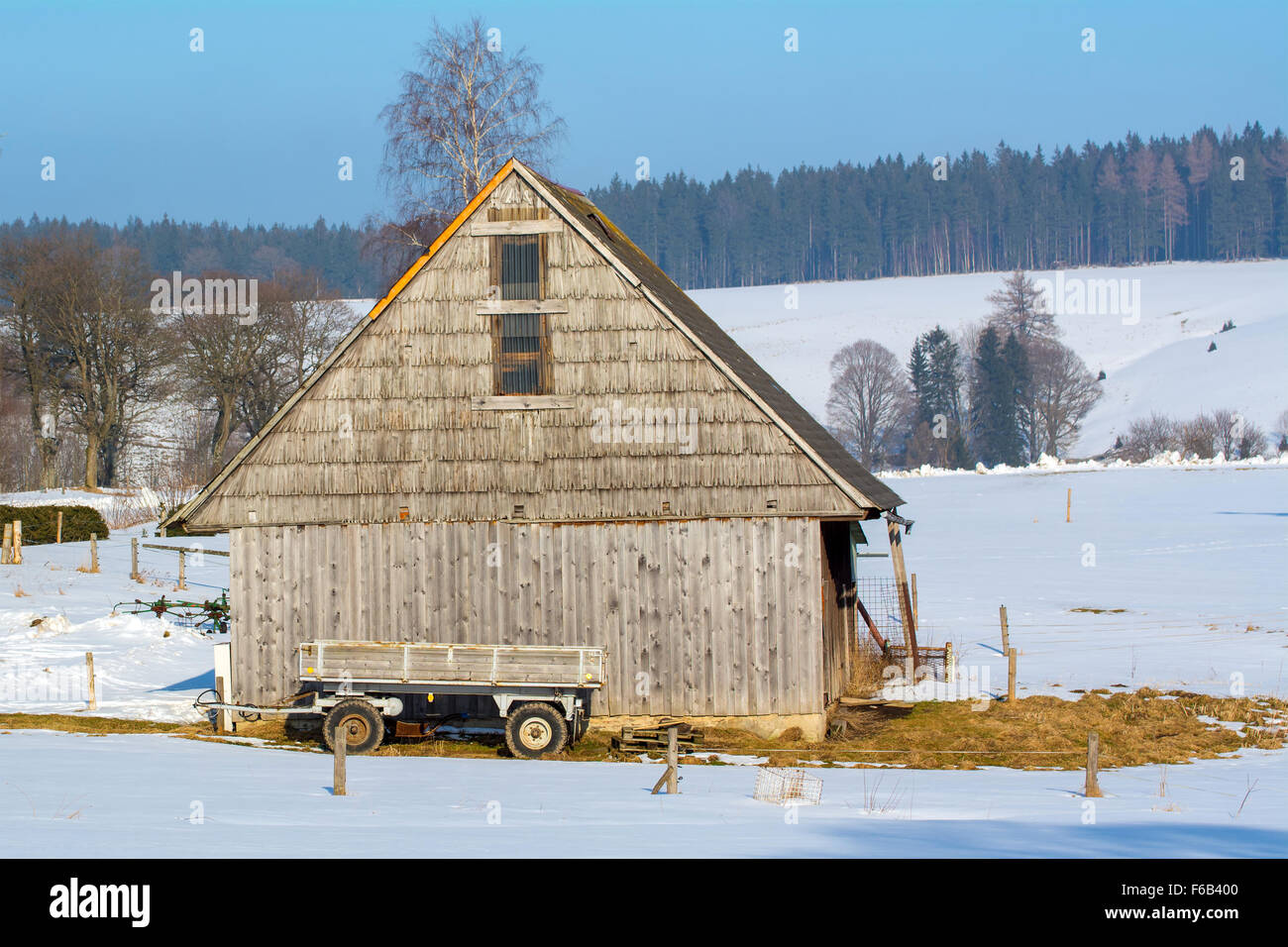 Old wooden barn with a wagon in the winter landscape Stock Photo