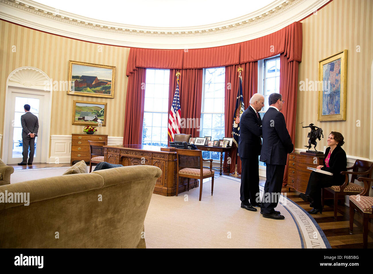 Brian Mosteller, Director of Oval Office Operations, looks out a window as Vice President Joe Biden and Defense Secretary Ashton Carter talk with Cecilia Mu–oz, Domestic Policy Council Director, in the Oval Office, Feb. 17, 2015. Stock Photo
