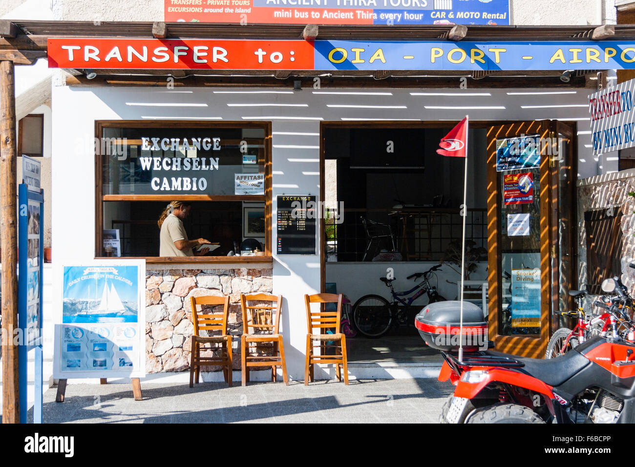 Santorini, Thira. Kamari. Tourist information centre building with currency exchange window, quad-hire bikes, and transfer service to airport. Stock Photo
