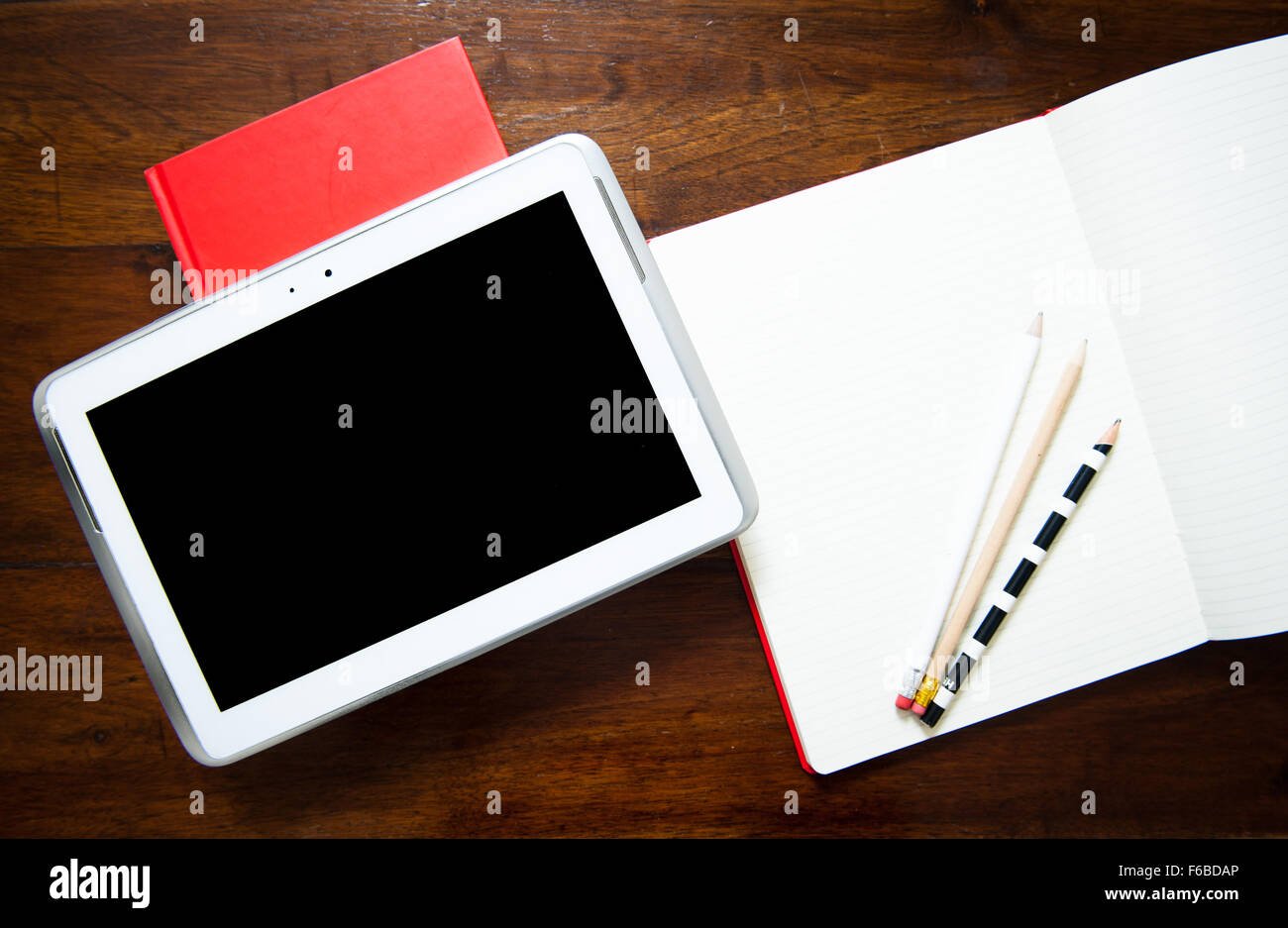Desktop detail with new electronic notepad and old fashoined note book and pencils Stock Photo