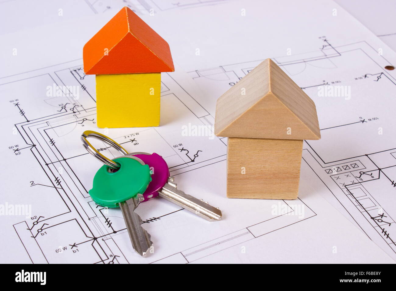Houses shape made of wooden blocks and home keys lying on electrical construction drawings of house, concept of building house, Stock Photo