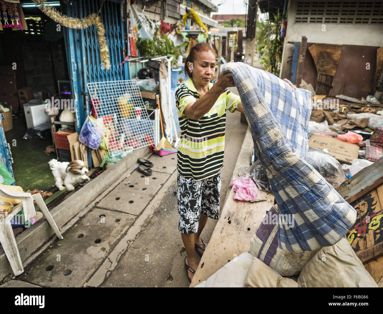 Nov. 12, 2015 - Bangkok, Bangkok, Thailand - A resident of the  Wat Kalayanmit neighborhood hangs out a quilt on the day she was being evicted. Fifty-four homes around Wat Kalayanamit, a historic Buddhist temple on the Chao Phraya River in the Thonburi section of Bangkok, are being razed and the residents evicted to make way for new development at the temple. The abbot of the temple said he was evicting the residents, who have lived on the temple grounds for generations, because their homes are unsafe and because he wants to improve the temple grounds. The evictions are a part of a Bangkok tre Stock Photo