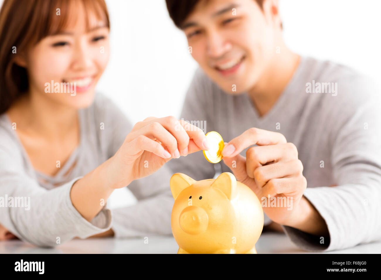 Happy young Couple Inserting Coin In Piggybank Stock Photo - Alamy