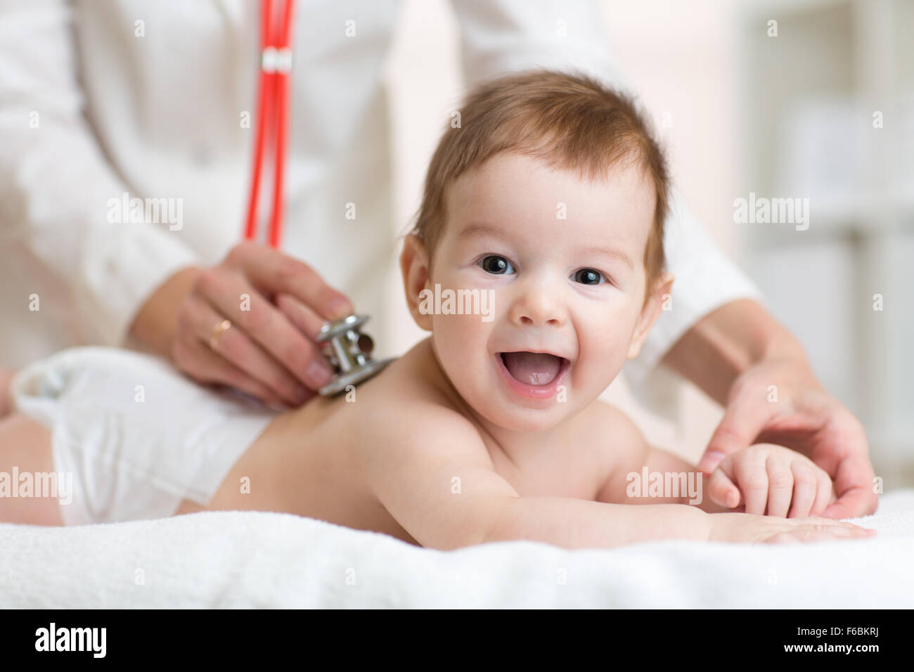 Pediatrician doctor examines baby with stethoscope checking heart beat