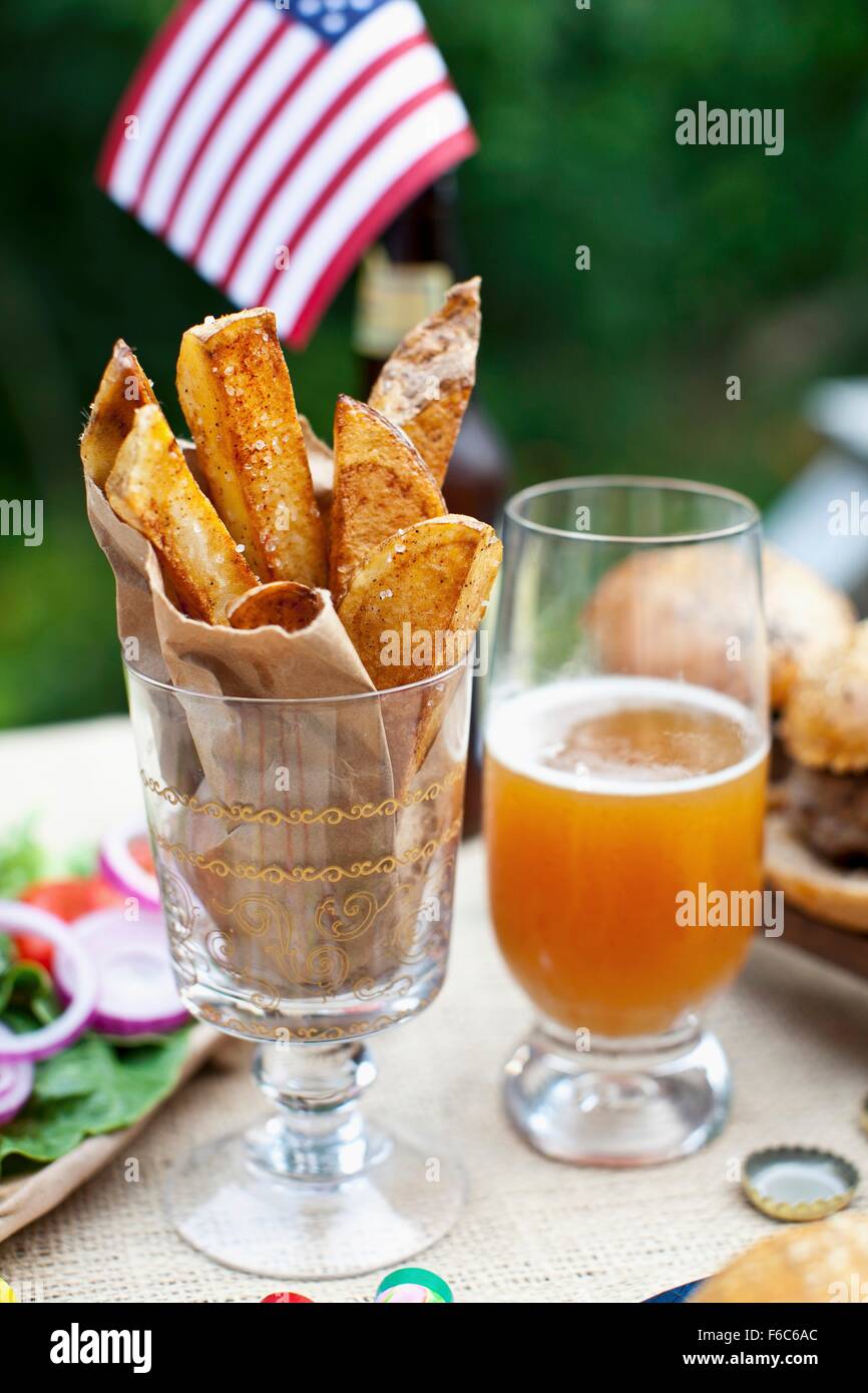 Potato wedges on a table outside, in the background buffalo burgers and a US flag Stock Photo