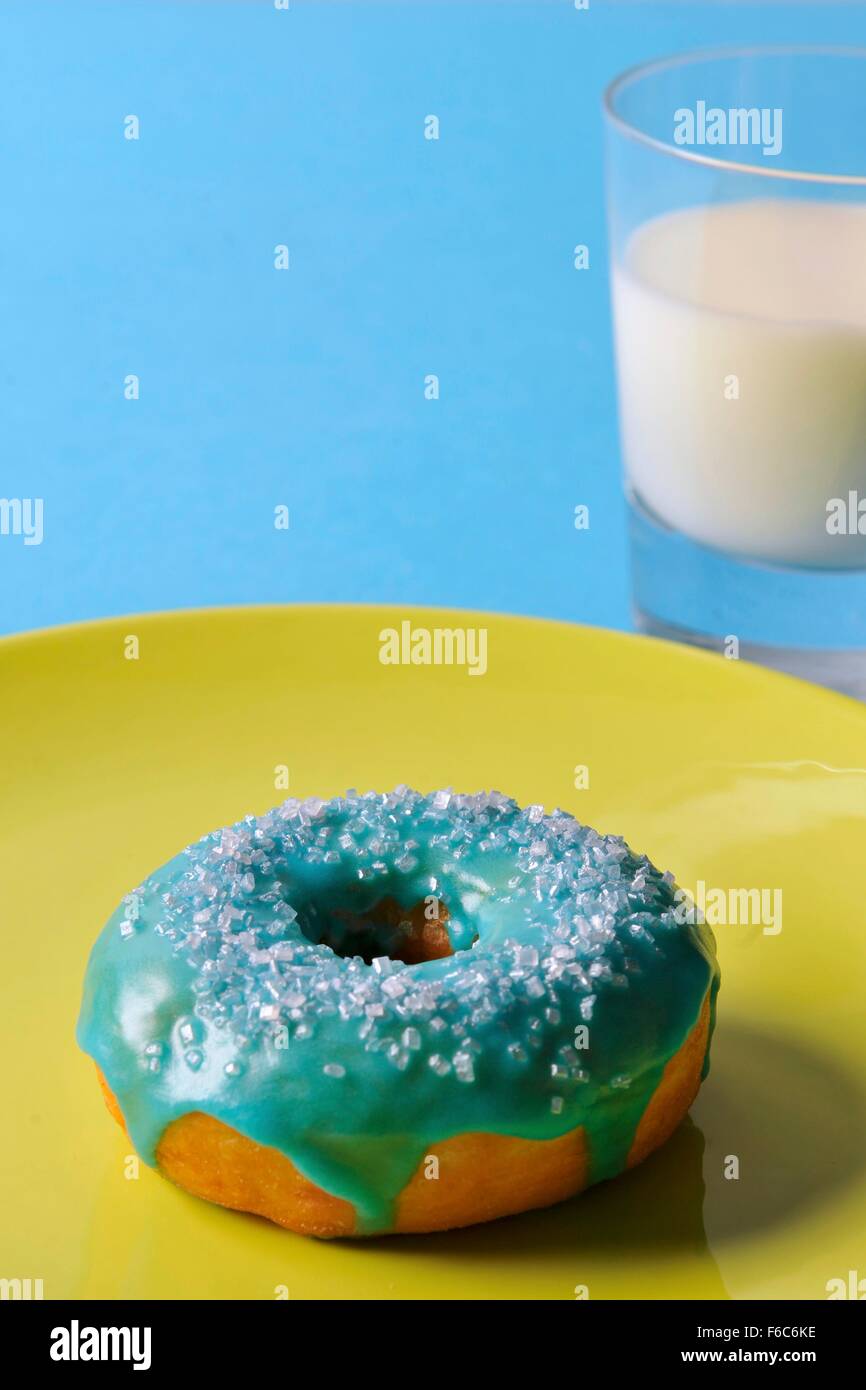A doughnut with blue glaze and a glass of milk Stock Photo