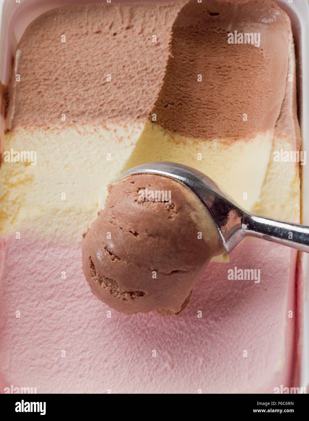 Neapolitan ice cream in a plastic box and an ice cream scoop Stock Photo