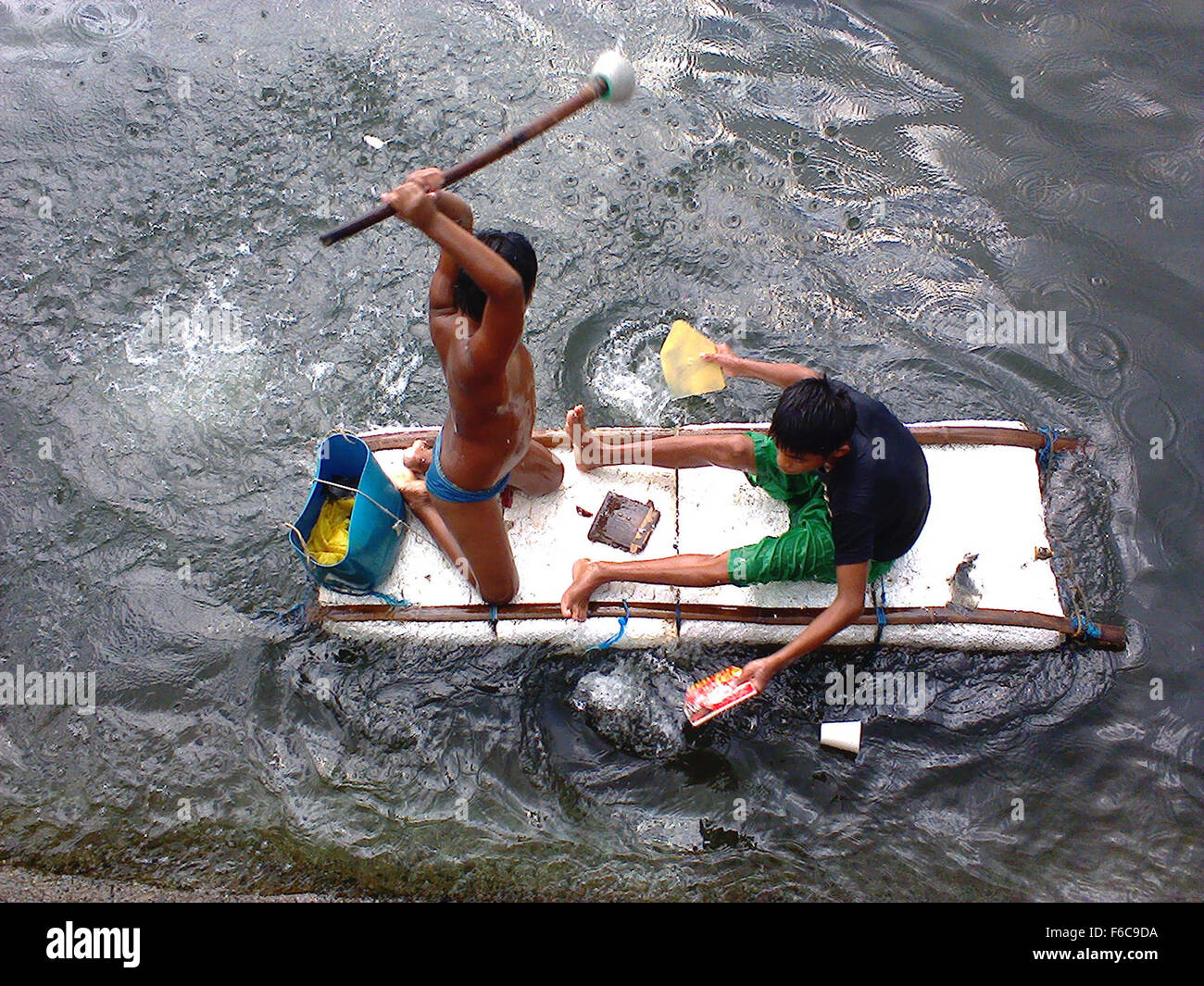 Filipino boys aboard an improvised raft paddle along the coast of ...