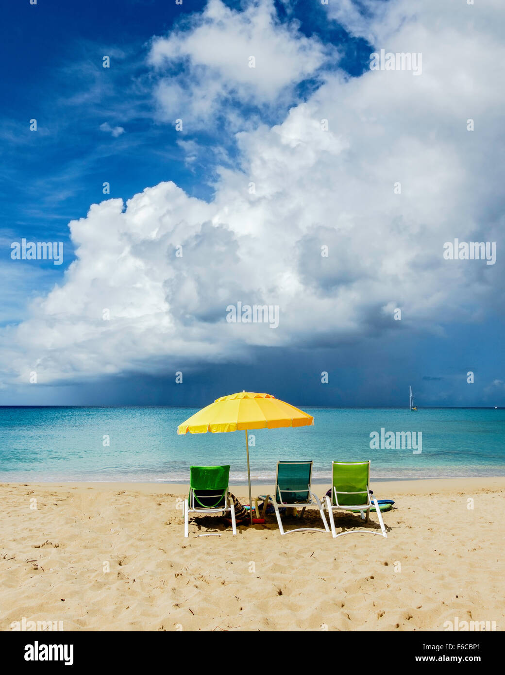 Three beach chairs under a yellow umbrella look out on a tropical storm over the Caribbean sea. St. Croix, U.S. Virgin Islands. USVI, U.S.V.I. Stock Photo