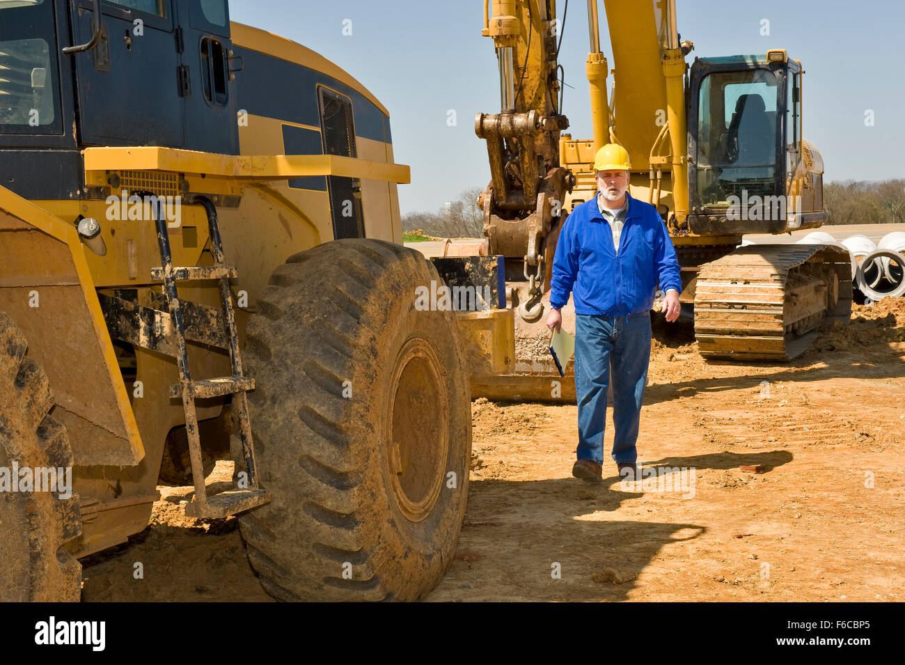 Heavy Equipment Operator Walks Between Equipment Stock Photo