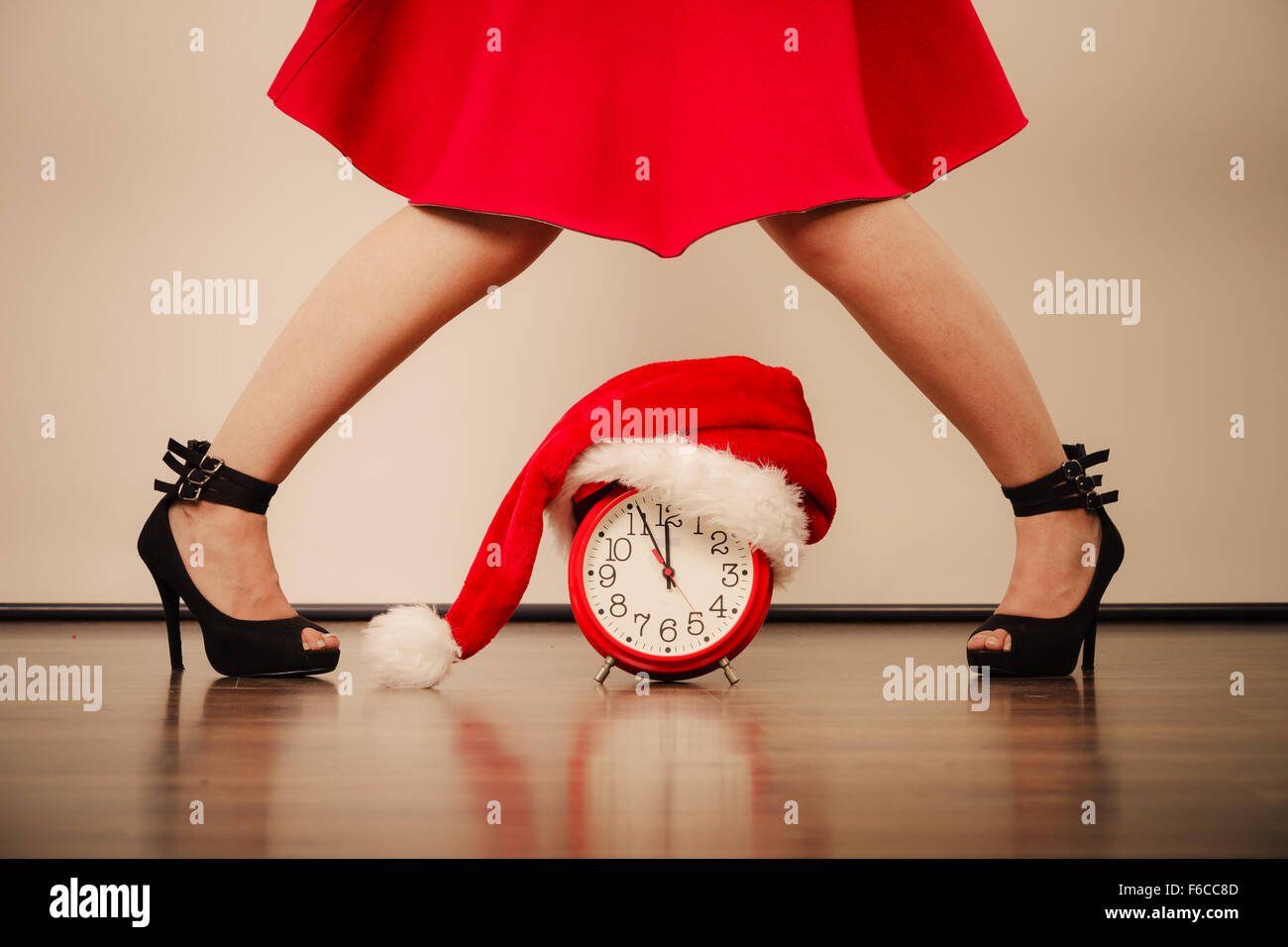 Closeup of woman in high heels and alarm clock with santa claus hat. Christmas time season concept. Stock Photo