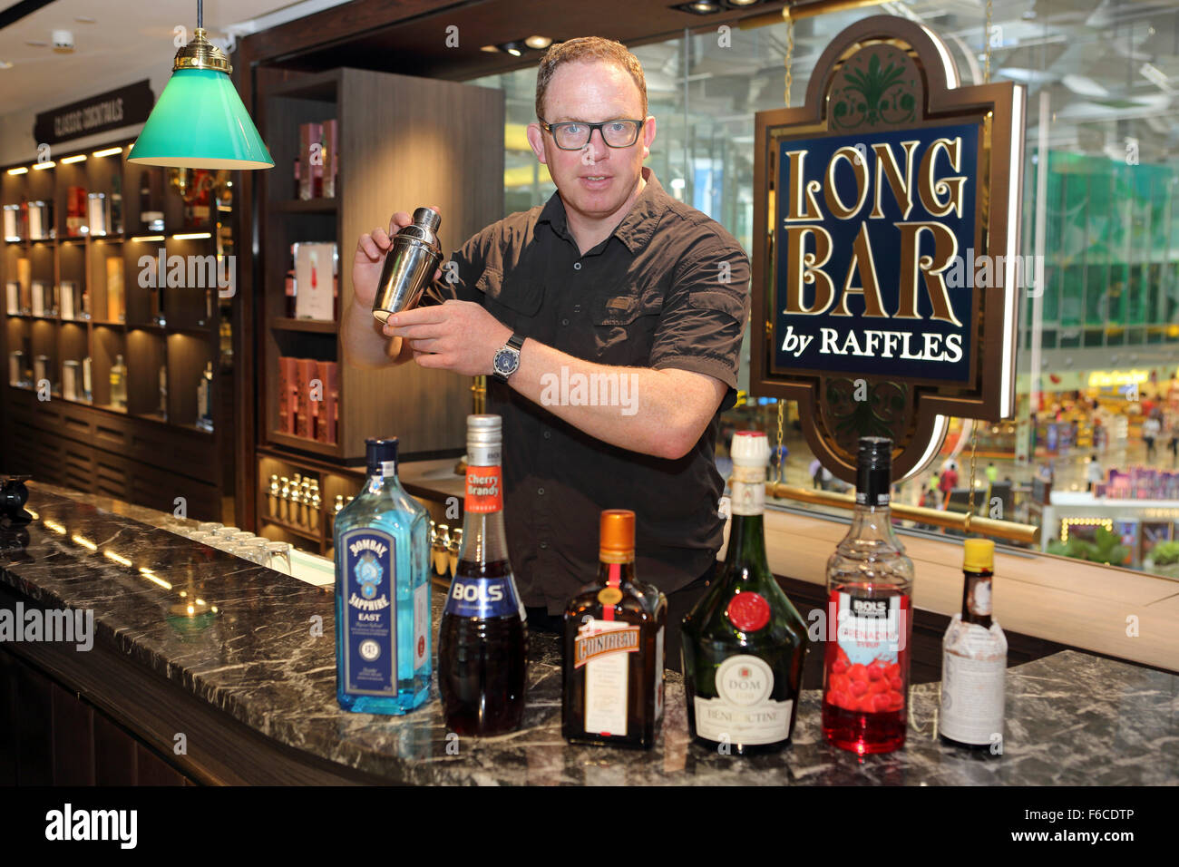 A man mixes a Singapore Sling cocktail at the Long Bar by Raffles at Changi International Airport in Singapore. Raffles is assoc Stock Photo