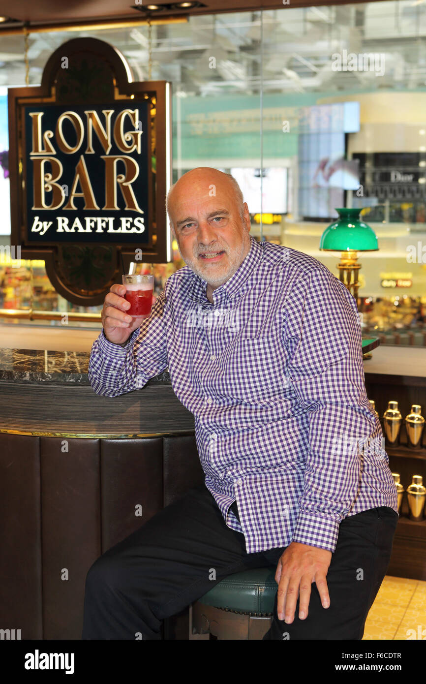 A man drinks a Singapore Sling cocktail at the Long Bar by Raffles at Changi International Airport in Singapore. Raffles is asso Stock Photo