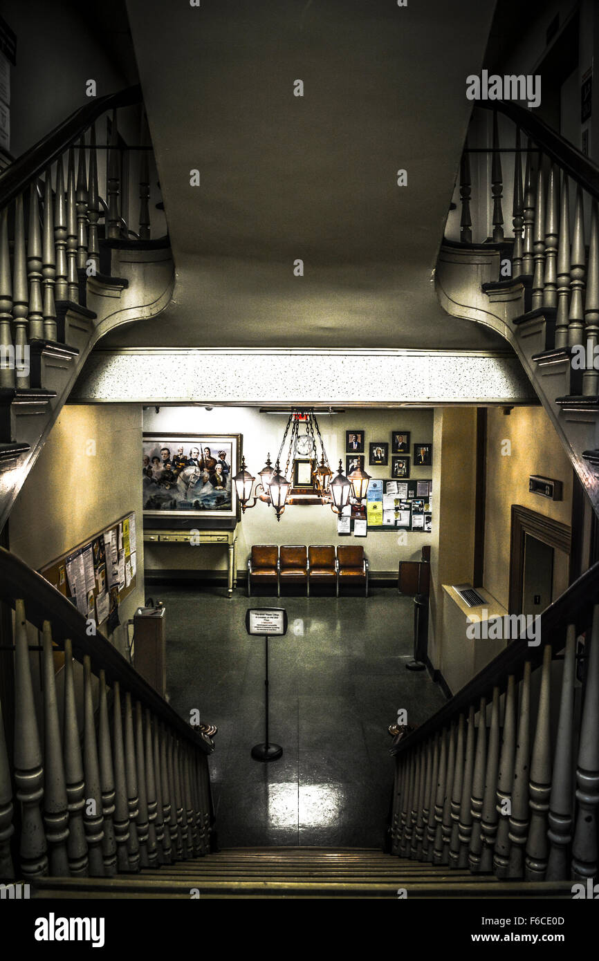 Interior of small town courthouse staircase viewed down from 1st floor with dramatic light and mysterious atmosphere Stock Photo