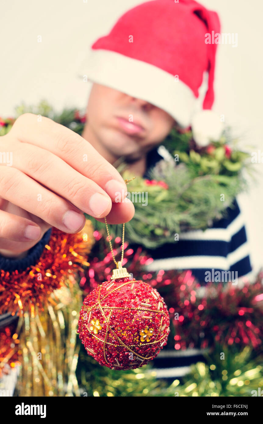 a young caucasian man wearing a santa hat covered with christmas ...