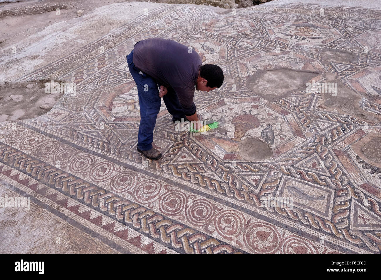 A worker of the Israel Antiquities Authority cleans a 1,700 year old mosaic, which served as pavement for the courtyard in a villa during the Roman and Byzantine periods in the Israeli central city of Lod Israel Stock Photo