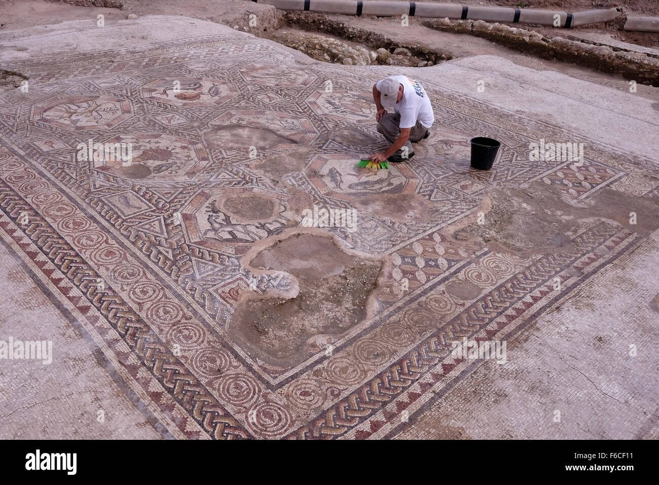 A worker of the Israel Antiquities Authority cleans a 1,700 year old mosaic, which served as pavement for the courtyard in a villa during the Roman and Byzantine periods in the Israeli central city of Lod Israel Stock Photo